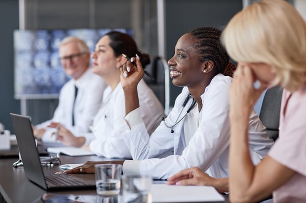 smiling-black-woman-asking-speaker-question-group-seminar-with-colleagues-office-room